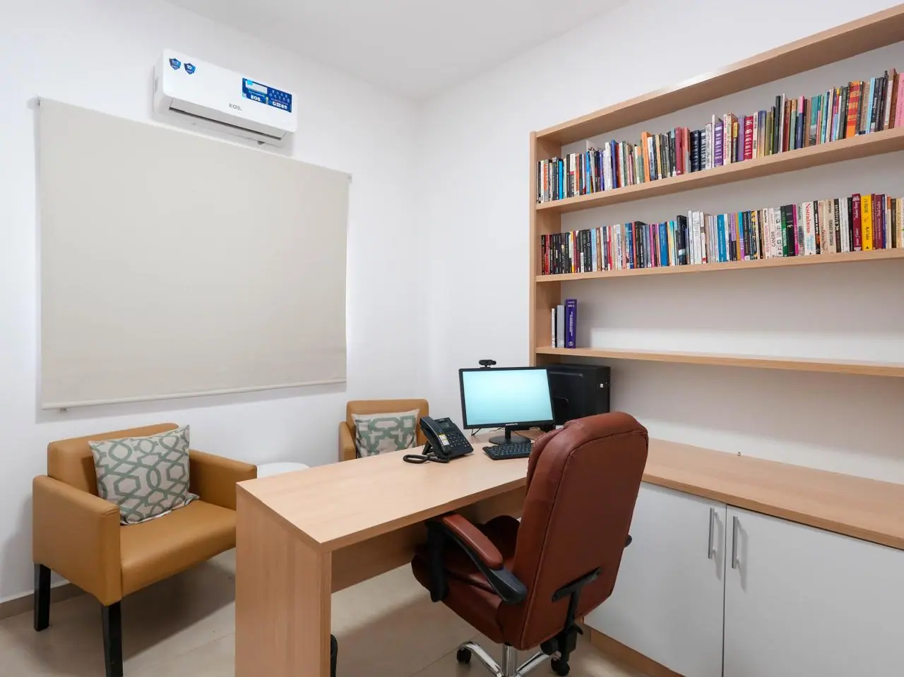 Biblioteca com estante de livros e estação de estudo na unidade Capela do Alto