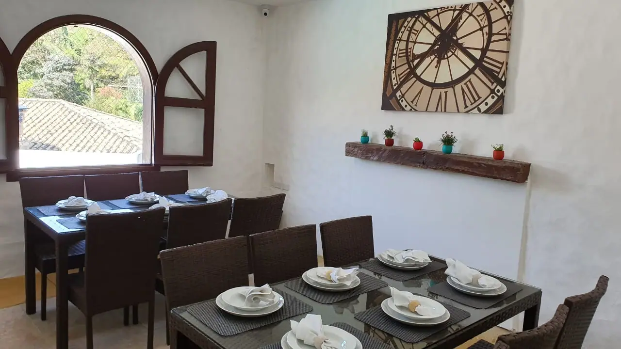 Sala de refeições com mesa posta e janela em arco na unidade Granja Viana