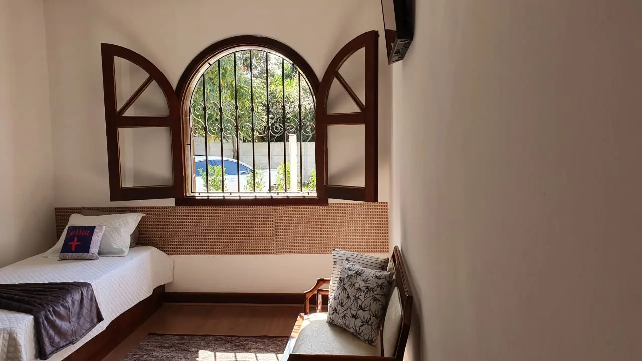 Quarto com janela em arco voltada para o jardim na unidade Granja Viana
