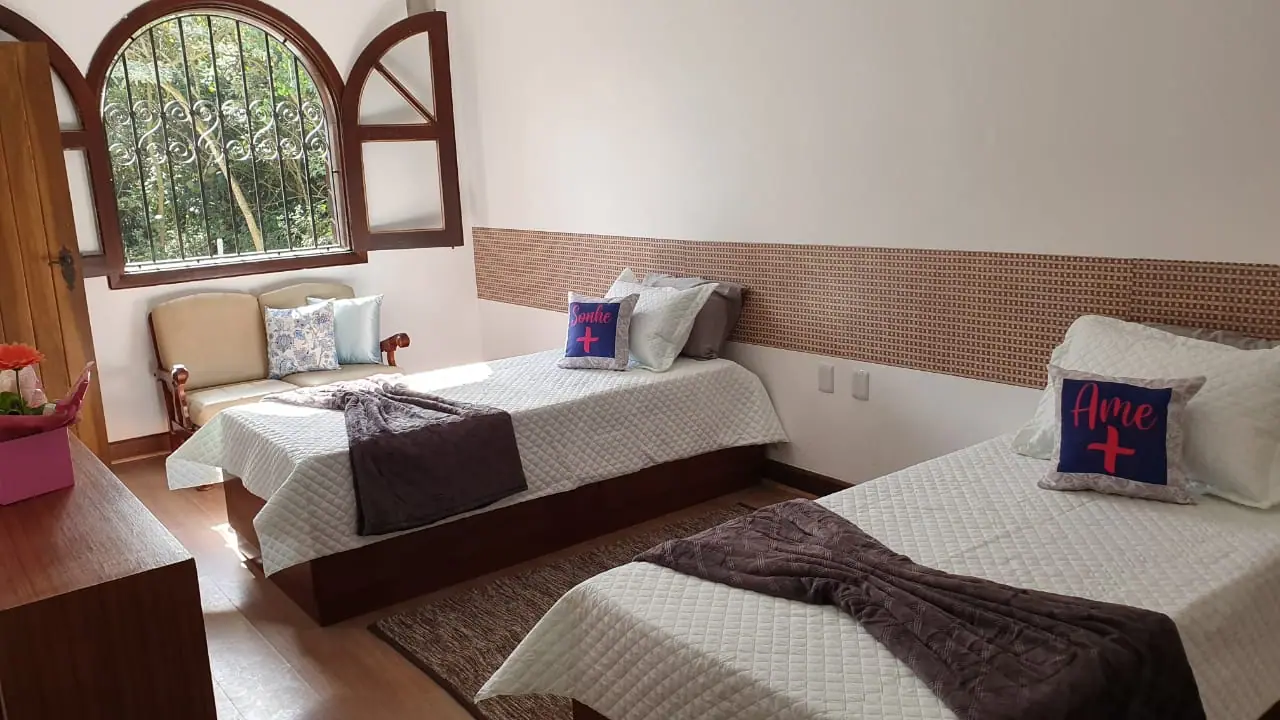 Quarto com duas camas e cabeceira de madeira na unidade Granja Viana