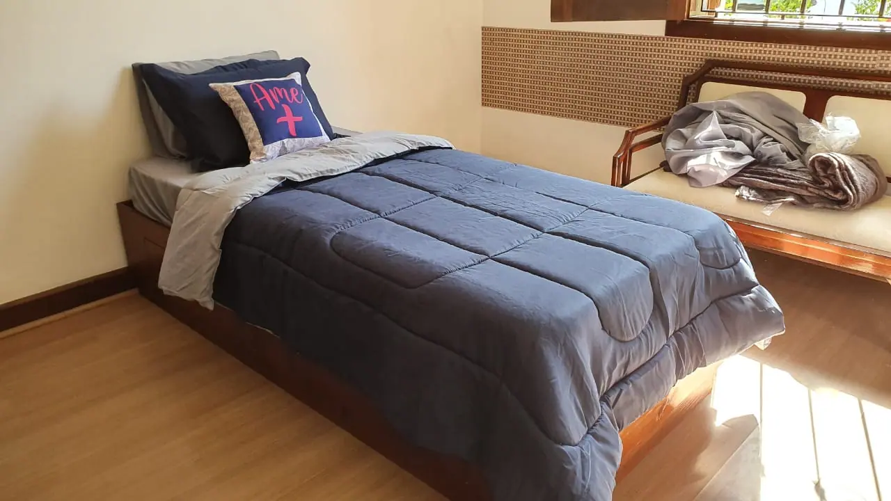 Quarto individual com roupa de cama cinza na unidade Granja Viana