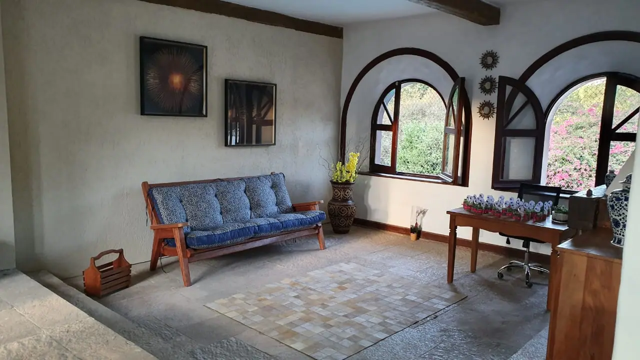 Sala de convivência com sofá e janelas em arco na unidade Granja Viana